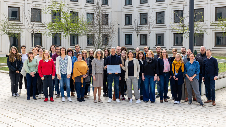 Viele Menschen, die sich an der Universität Mannheim für Diversität engagieren, stehen um Thomas Fetzer, der das Zertifikat des Stifterverbandes in Händen hält.