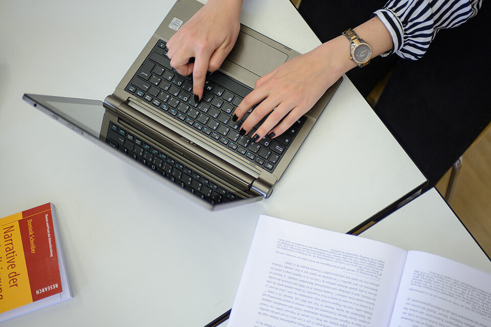 Zwei Hände einer Frau tippen auf der Tastatur eines Laptops.