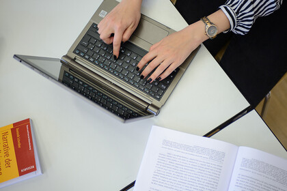 Zwei Hände einer Frau tippen auf der Tastatur eines Laptops.