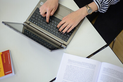 Zwei Hände einer Frau tippen auf der Tastatur eines Laptops.