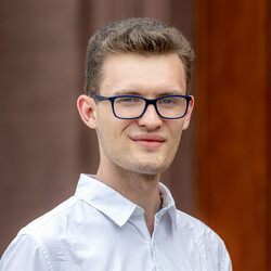 Marc Hattermann. Die Person trägt Brille, ein weißes Hemd und lächelt in die Kamera