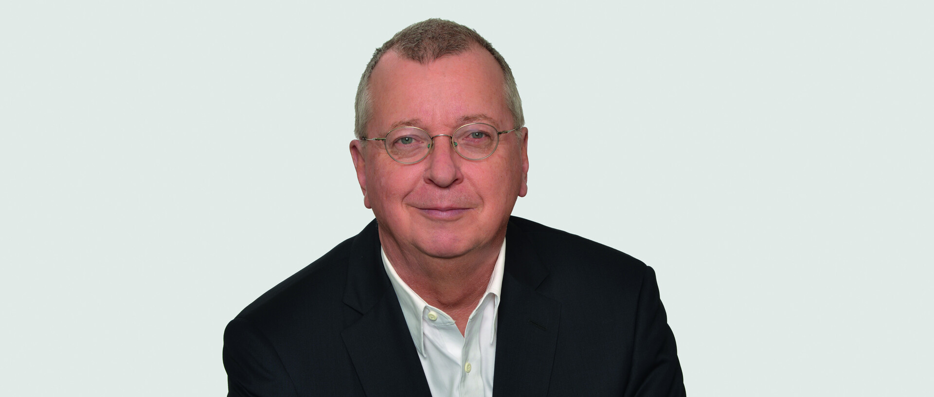 Prof. Dr. Dr. h. c. Martin Weber mit kurzen hellbraunen Haaren, einer runden goldenen Brille und schwarzem Anzug im Porträt vor einer weißen Wand