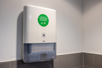 Einer der neuen Papierspender mit recyceltem Handtuchpapier in einer Toilette der Universität. Ein grüner Aufkleber weist auf das Recycling-Programm hin.