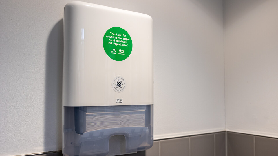 Einer der neuen Papierspender mit recyceltem Handtuchpapier in einer Toilette der Universität. Ein grüner Aufkleber weist auf das Recycling-Programm hin.