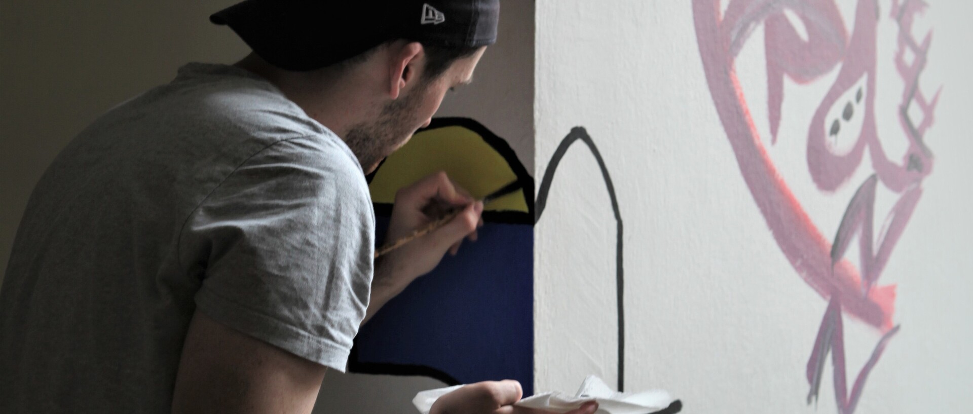 Eine Person malt an einer Wand.