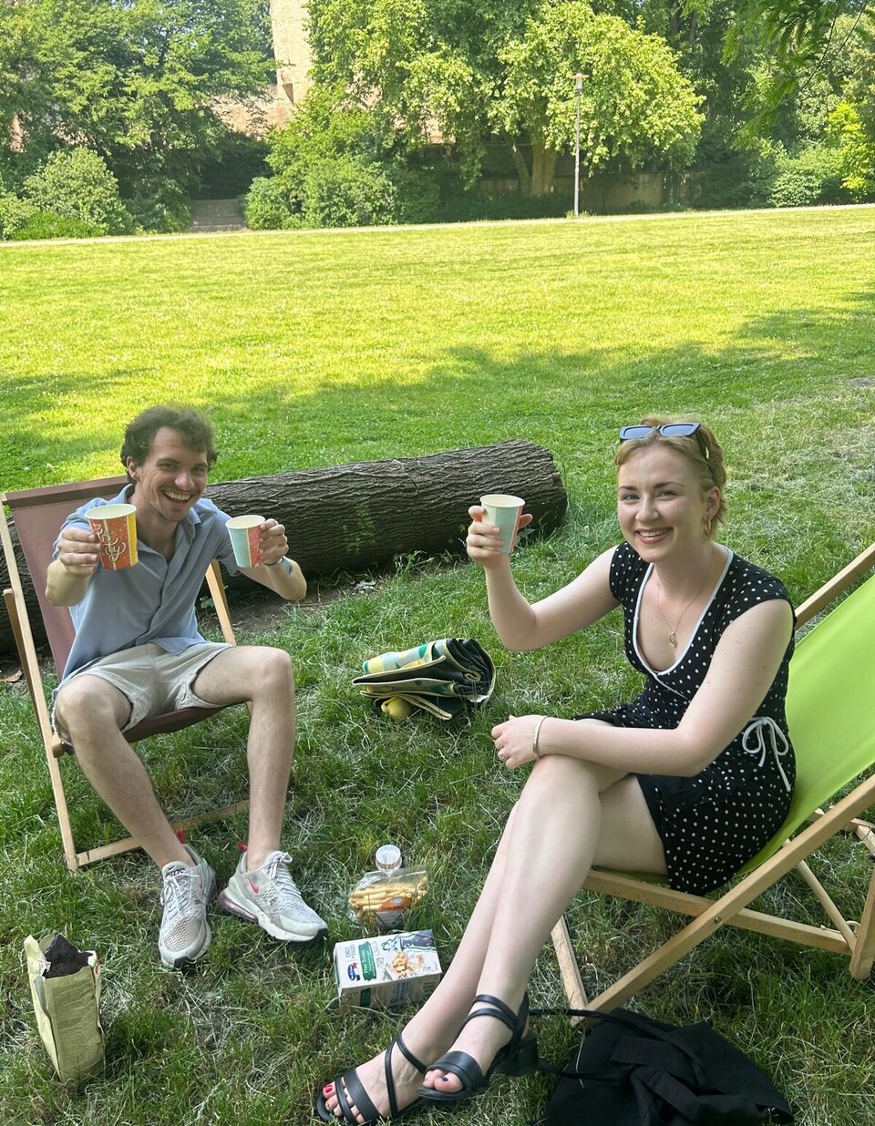 Studierende mit Getränken in zwei Stühlen im Domgarten