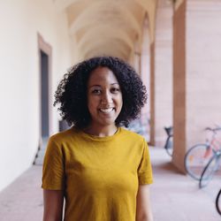 Ein Porträtfoto von Mariel Loko. Sie hat schwarze, lockige Haare und trägt ein senfgelbes T-Shirt.