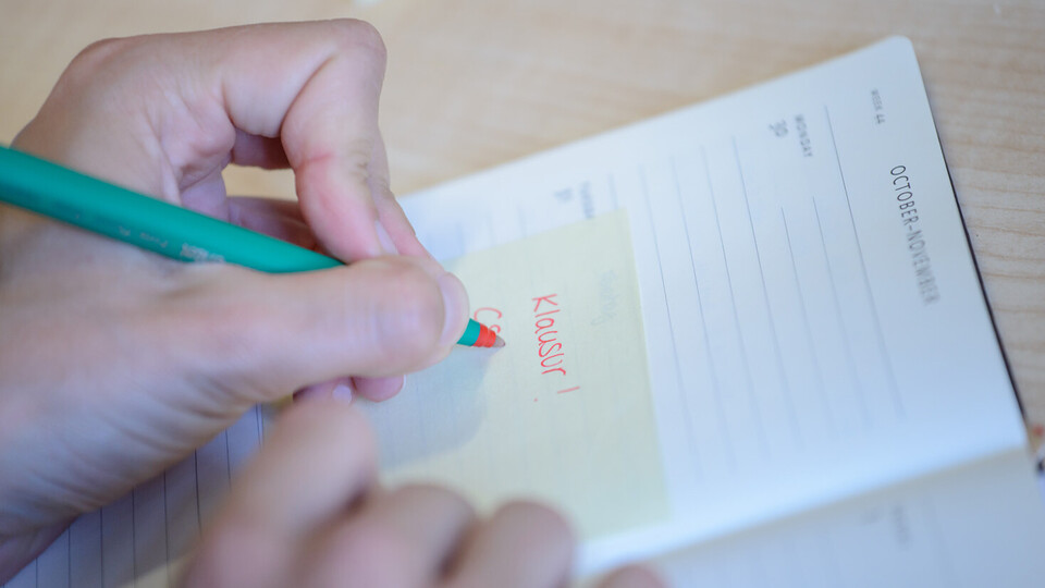 Eine Person trägt einen Termin in einen Kalender ein.
