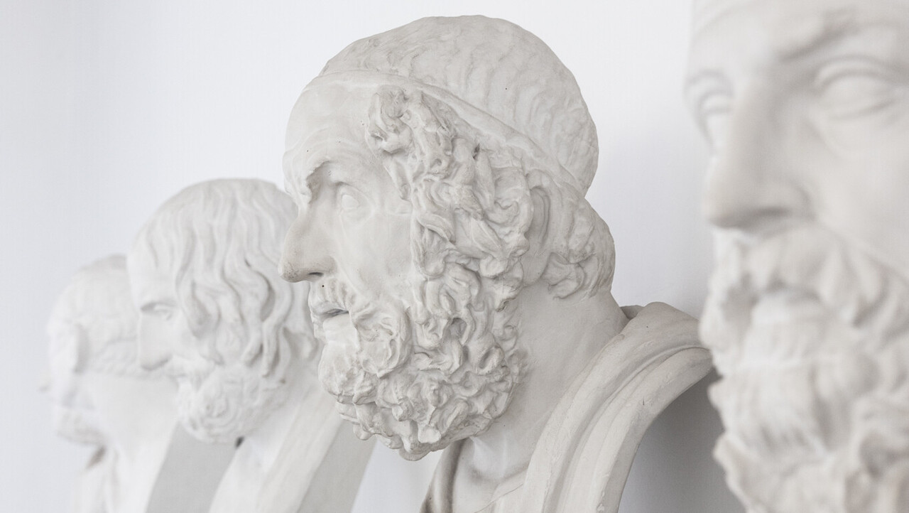 Vier antike Büsten von Männern sind nebeneinander aufgestellt.