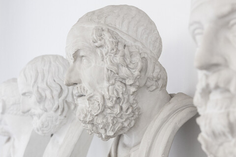 Vier antike Büsten von Männern sind nebeneinander aufgestellt.