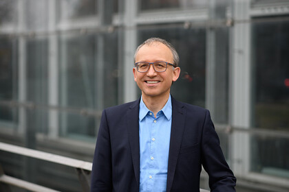 Thomas Gschwend.  He is wearing a blue suit and is standing outside of the A5 building.