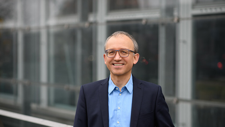 Thomas Gschwend. He is wearing a blue suit and is standing outside of the A5 building.