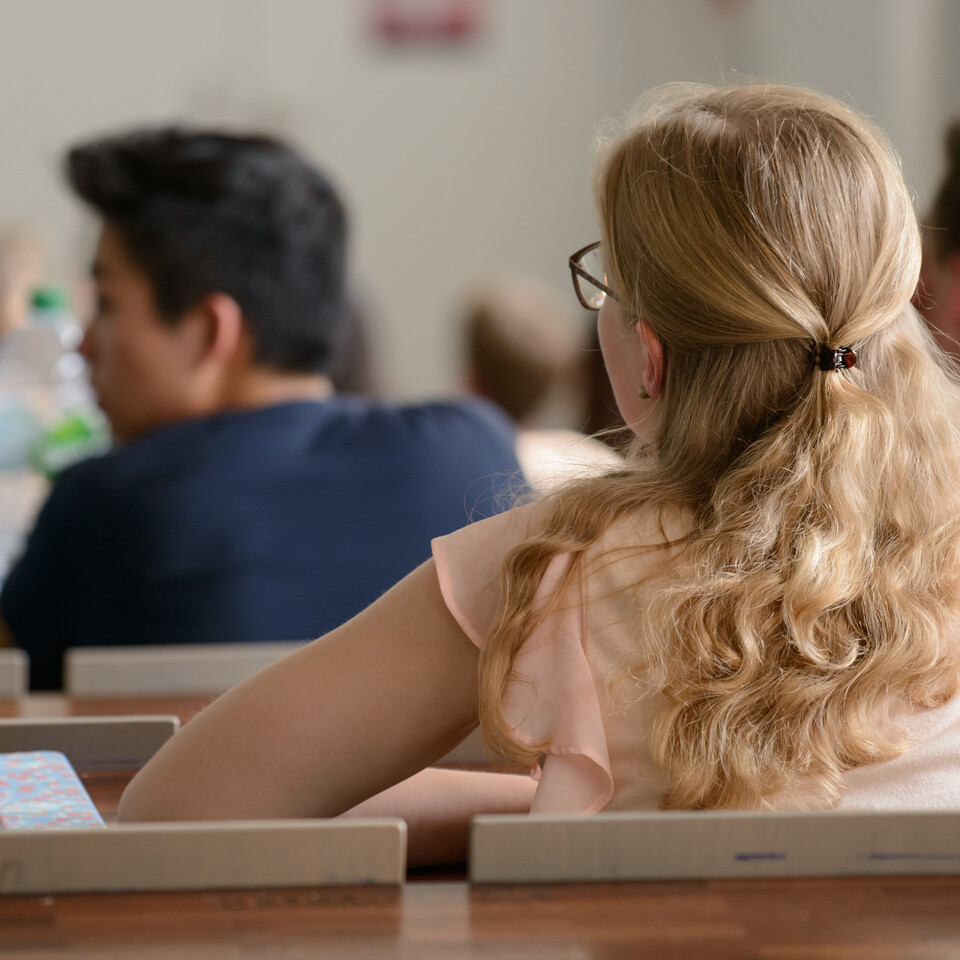 Studierende sitzen in einem Hörsaal und hören einer Veranstaltung zu.