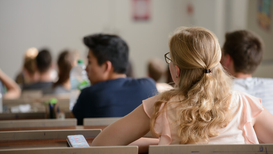 Studierende sitzen in einem Hörsaal und hören einer Veranstaltung zu.