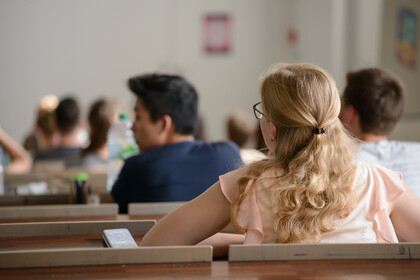 Studierende sitzen in einem Hörsaal und hören einer Veranstaltung zu.