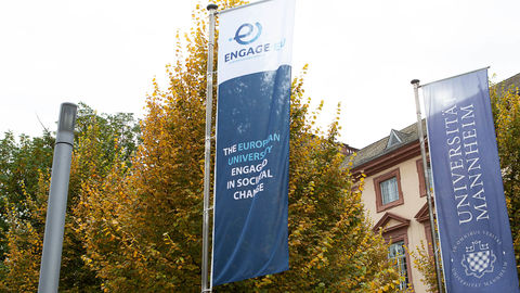 Die Fahnen von Engage.Eu sowie der Uni Mannheim stehen nebeneinander vor dem Schloss der Uni.