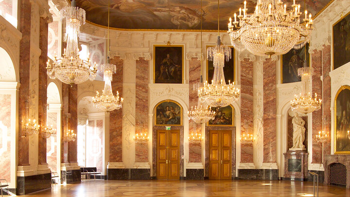 Rittersaal des Mannheimer Schloss. Mehrere Kronleuchter hängen von der Decke. An den Wänden hängen Gemälde der Barockzeit.