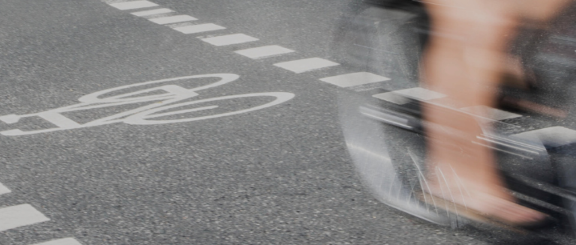 dynamische Nahaufnahme radelnder Beine auf einem markierten Radweg