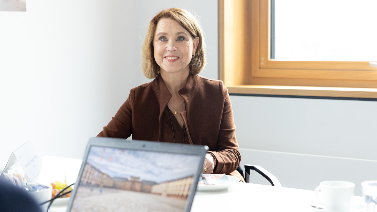 Petra Olschowski sitzt an einem Tisch, auf dem ein Tablet steht.