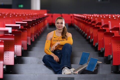 Eine Leichtathletikerin sitzt mit Startblöcken auf den Treppen eines Vorlesungssaals.