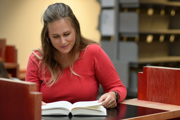 Studentin liest ein Buch in der Bibliothek der Universität Mannheim