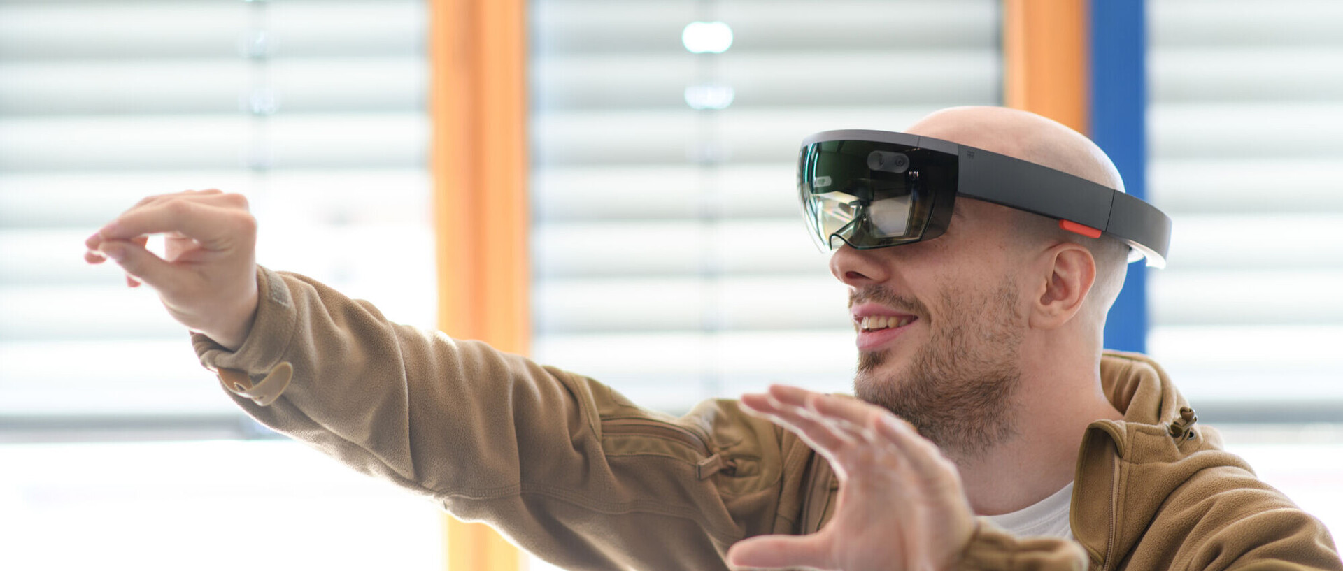 Ein Mensch trägt eine Virtual-Reality-Brille und hebt seine Hände hoch.