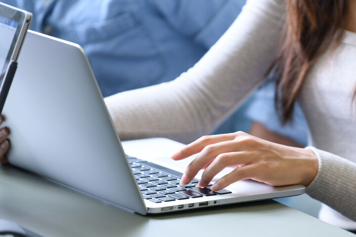Hands of a person writing on a laptop
