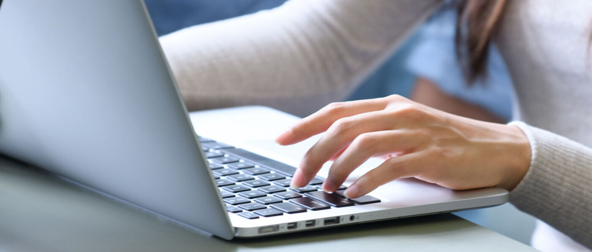 Hands of a person writing on a laptop