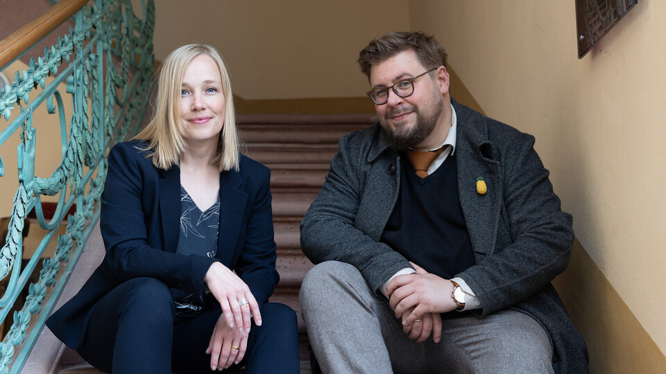 Julia Derkau und Hiram Kümper sitzen gemeinsam auf einer Treppe. 