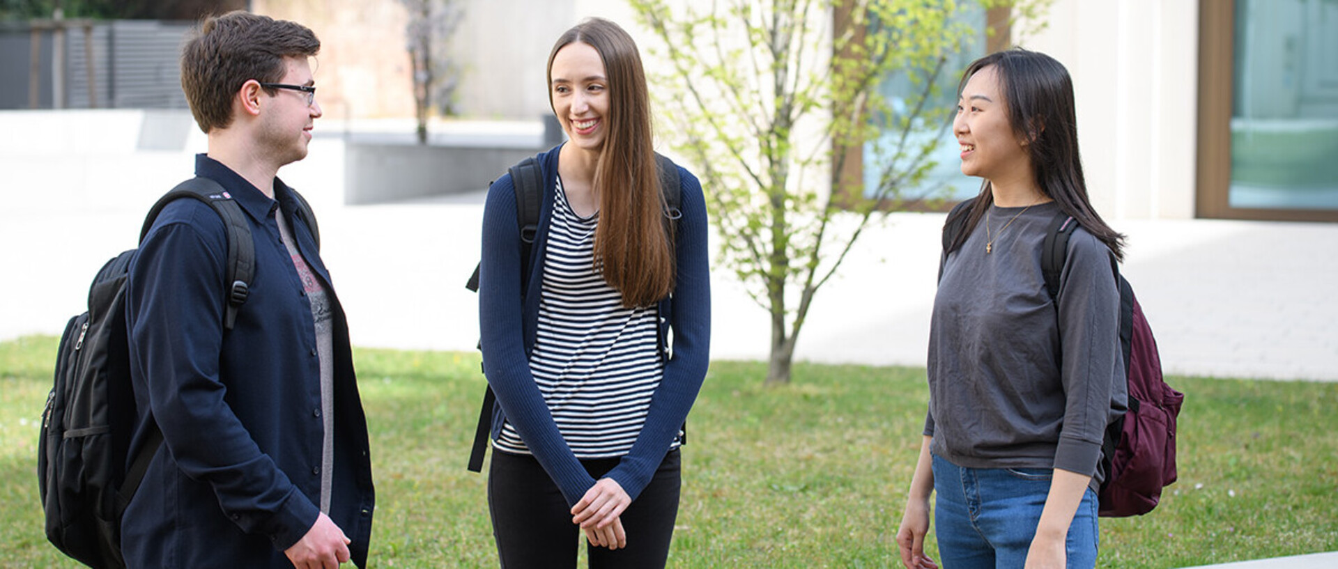 A group of doctoral students are talking in the courtyard of B6,30-32.