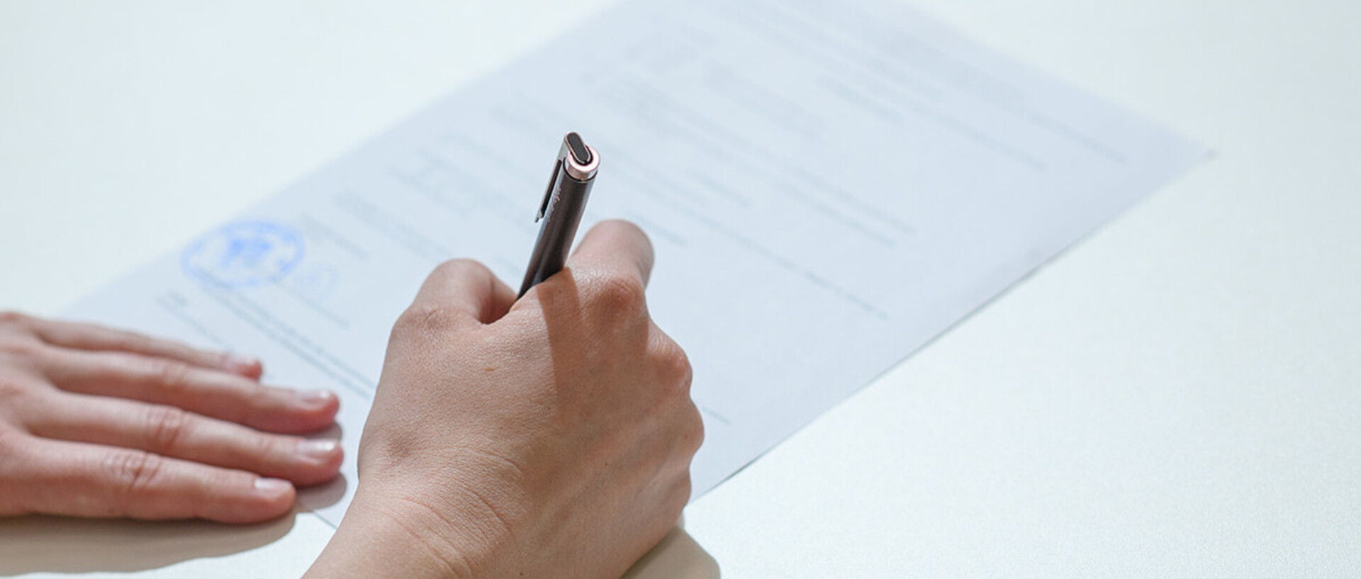 A person is filling out a paper form with a pen.