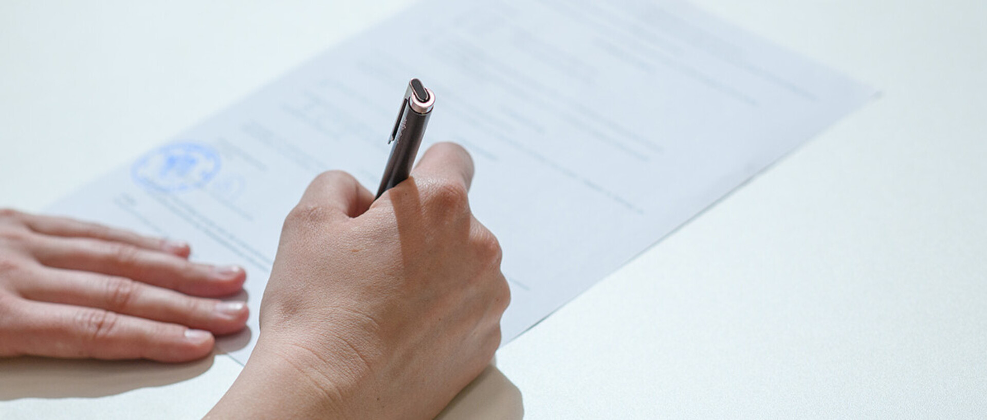 A person is filling out a paper form with a pen.