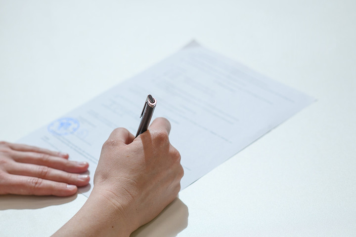 A person is filling out a paper form with a pen.