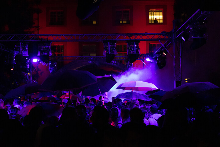 Eine Menschenmenge im düsteren lila und roten Scheinwerferlicht auf dem Schneckenhof.