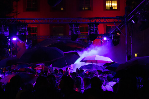 Eine Menschenmenge im düsteren lila und roten Scheinwerferlicht auf dem Schneckenhof.