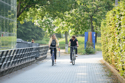 Eine Studentin und ein Student fahren Rad. Sie sind vor dem Gebäude A5. 