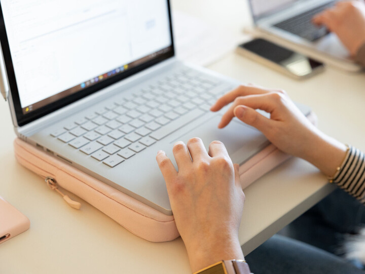 Hände tippen auf einer Laptoptastatur.