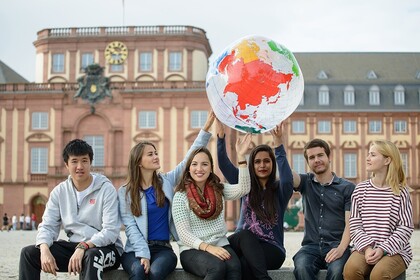 Abgebildet ist eine Gruppe von Studierenden, die gemeinsam eine Weltkugel hochhalten.