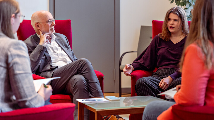 Rektor Prof. Dr. Thomas Puhl und AStA-Vorsitzende Clara Schünemann sitzen in einer Interview-Situation in Puhls Büro auf roten Sesseln.