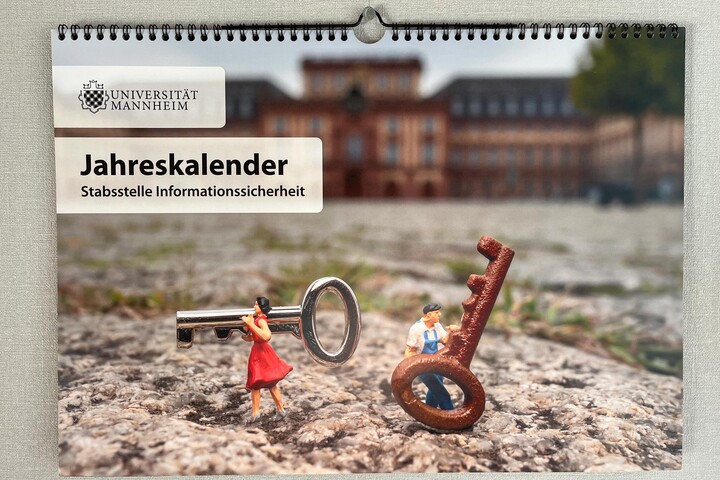Titelbild des Jahreskalenders der Stabsstelle Informationssicherheit. Zu sehen sind zwei Miniatur-Figuren, die Schlüssel vor dem Schloss Mannheim tragen.