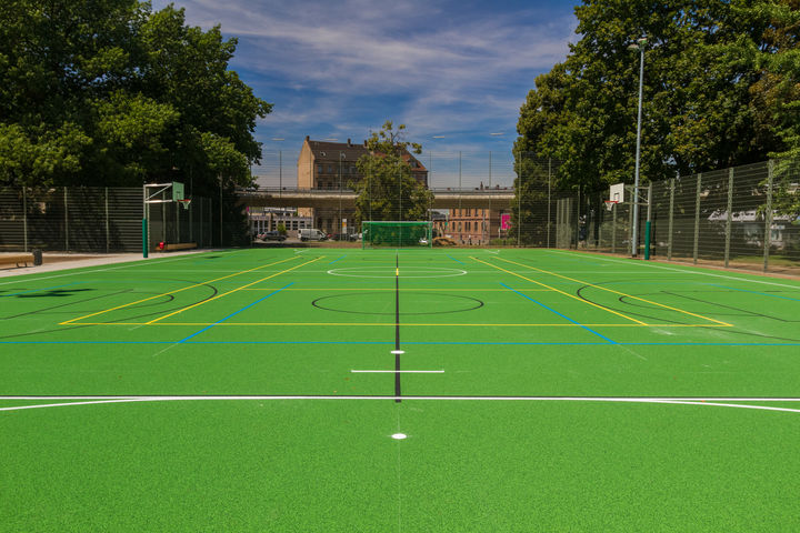 Alfred-Delp-Sportanlage im Friedrichspark. Grüner Hartboden mit Basketball- und Fußball-Toren