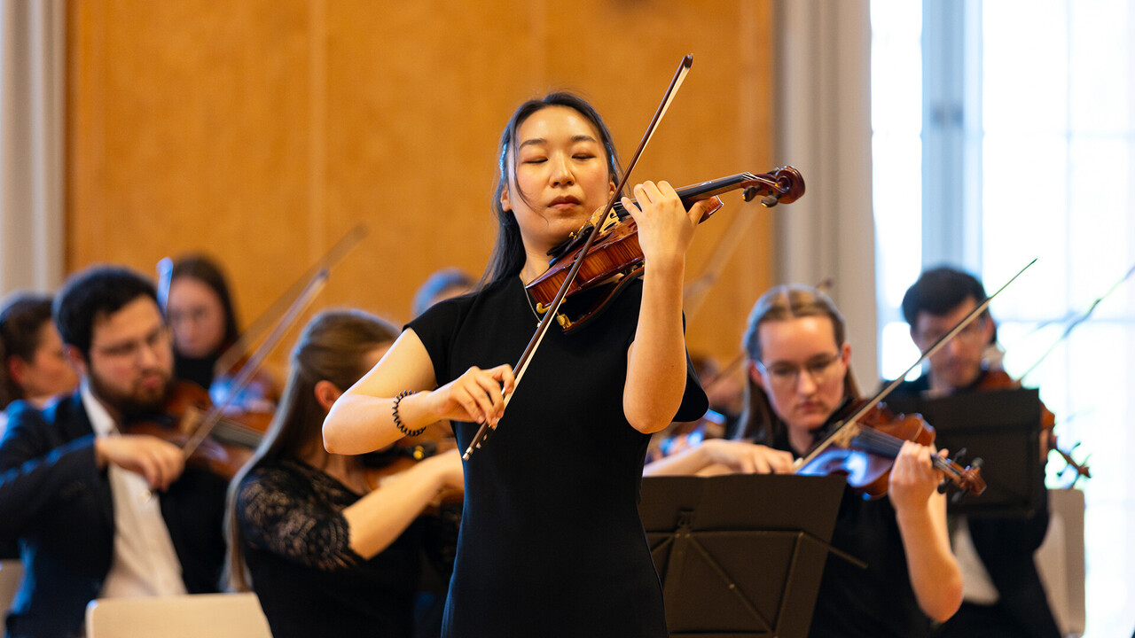 Auftritt des Uniorchesters. Viele Personen spielen Geige.
