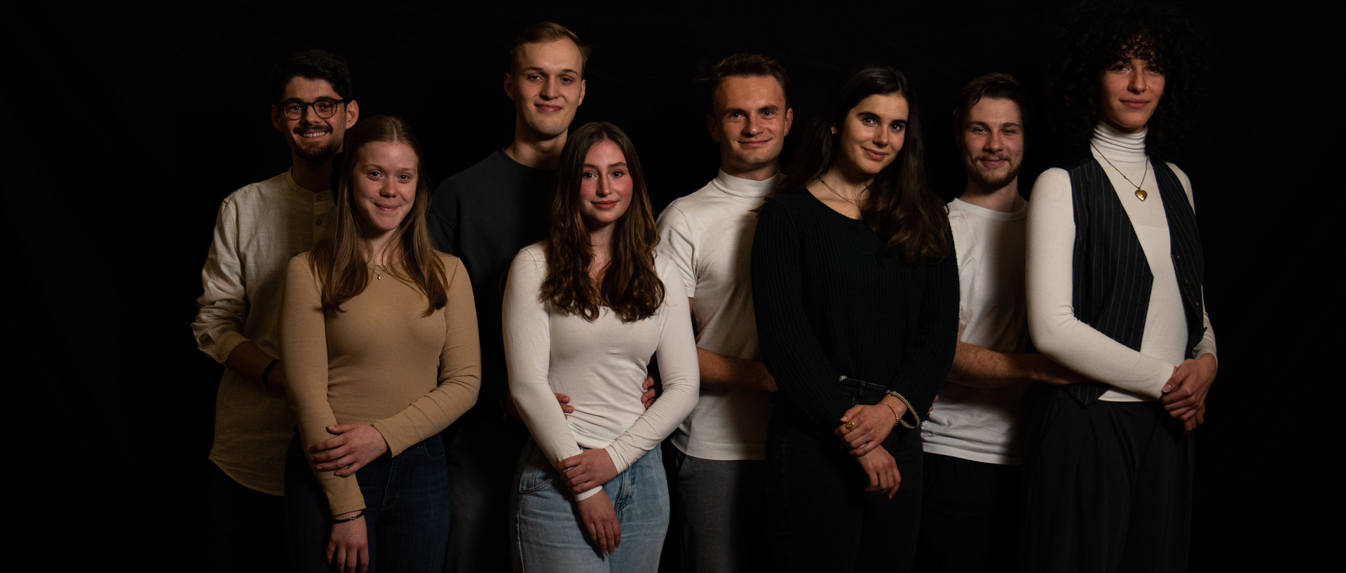 Eine Theatergruppe aus Männern und Frauen posiert für die Kamera.