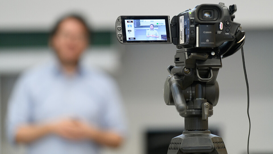 Eine Videokamera zeichnet den Vortrag einer Person auf.