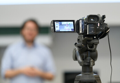 Eine Videokamera zeichnet den Vortrag einer Person auf.