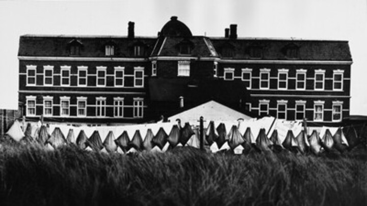 Schwarz-weiß Foto: Vor einem schwarzen Hotel hängt Wäsche auf einer Leine.