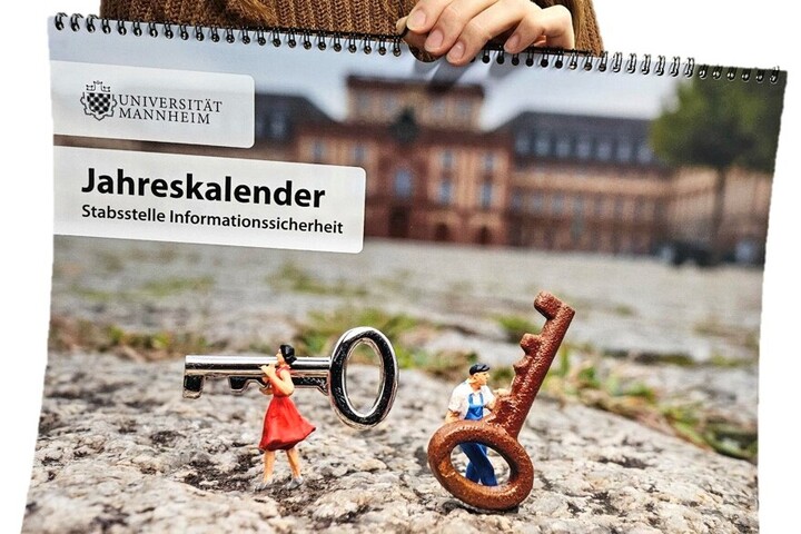 Eine Hand hält den Jahreskalender Stabsstelle Informationssicherheit mit dem Logo der Uni Mannheim. Auf dem Cover zwei Miniatur-Figuren vor dem Mannheimer Schloss, die jeweils einen Schlüssel in der Hand halten. 