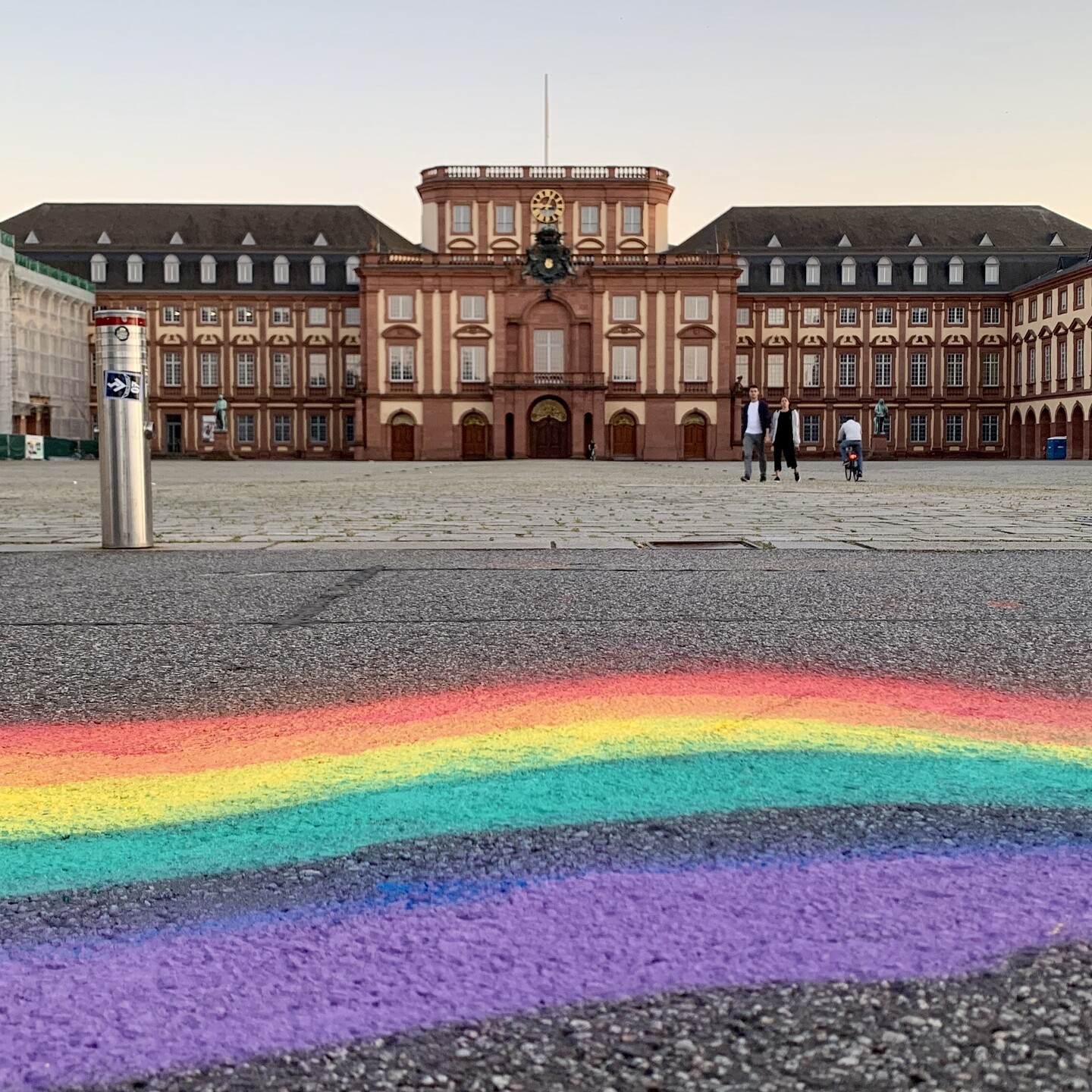 Ein Regebogen ist mit Kreide oder Sprühfarbe auf den Asphalt vor dem Ehrenhof gemalt.