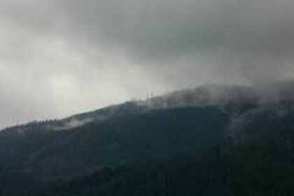 Eine Hügellandschaft in dunklen Wolken und Nebel eingehüllt.