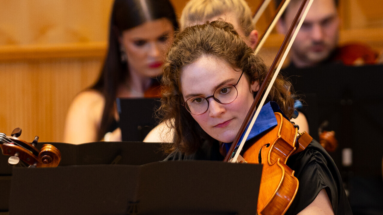Auftritt des Uniorchesters. Studierende sind schwarz gekleidet und spielen jeweils ein Instrument.